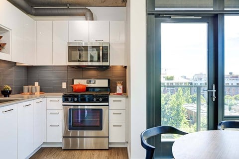 A modern kitchen with a stainless steel oven and white cabinets.