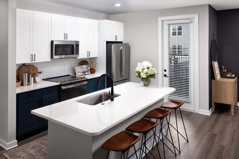 A kitchen with a white countertop and brown bar stools.