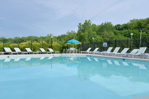 A large swimming pool with sun loungers and a blue umbrella.