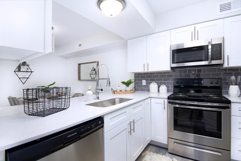 A modern kitchen with white cabinets and stainless steel appliances.