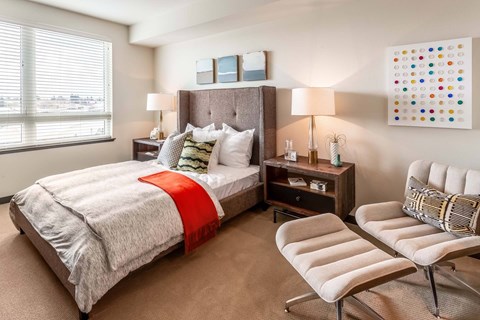 A bedroom with a large bed and a chair.