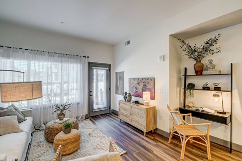 A living room with a white sofa, a wooden chair, and a wooden table with a vase on it.