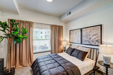 A bedroom with a large bed and a potted plant.