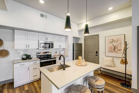 A modern kitchen with a white countertop and stainless steel appliances.