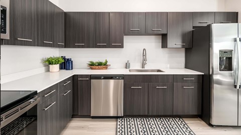 A modern kitchen with dark wood cabinets and stainless steel appliances.