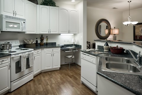 A kitchen with white cabinets and black countertops.