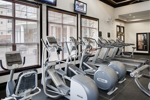 A gym with treadmills, exercise bikes, and a television.