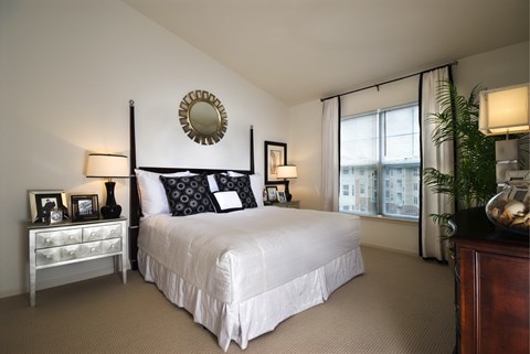 A bedroom with a large bed, a mirror, and a dresser.