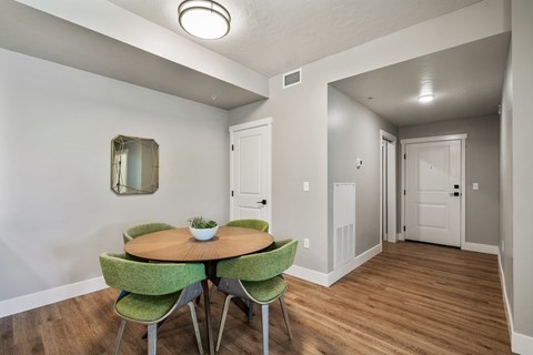 A dining room with a round table and green chairs.