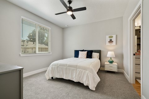 A bedroom with a white bed and a ceiling fan.