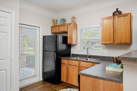 A kitchen with wooden cabinets and a black fridge.