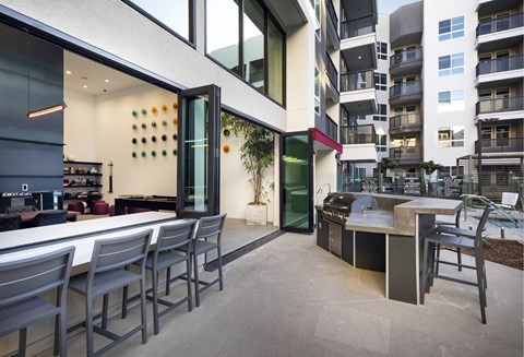 A modern outdoor kitchen area with a bar and chairs