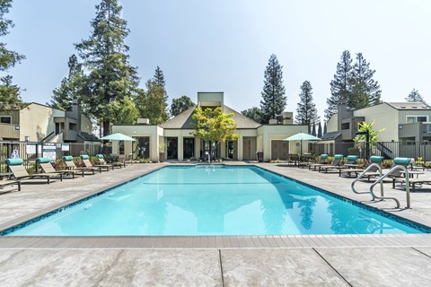 A large swimming pool in front of a building surrounded by trees.