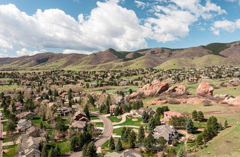 A small town with houses and trees in the foreground and mountains in the background.
