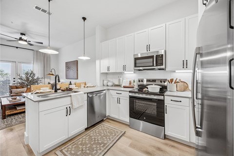 A modern kitchen with white cabinets and stainless steel appliances.