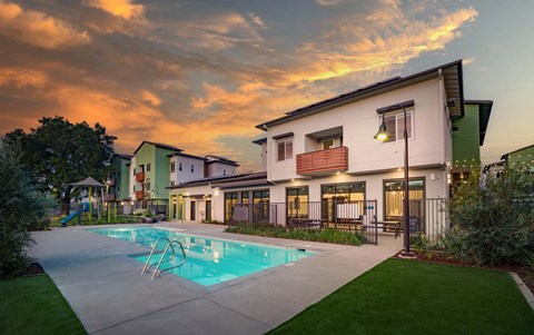 A swimming pool is in front of a house.