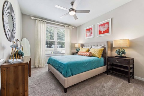 A bedroom with a bed, nightstand, and a ceiling fan.