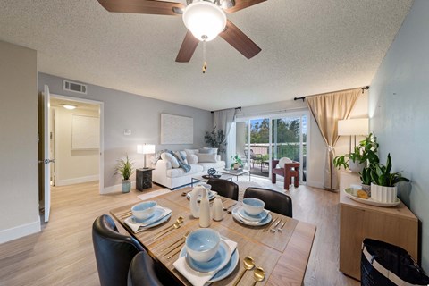 A dining room with a table set for two and a view of the backyard.