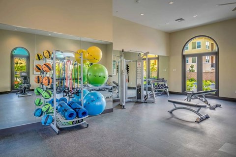 A gym with a variety of exercise equipment including a bench, weights, and exercise balls.