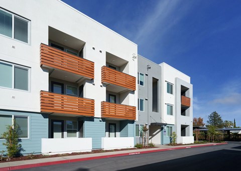 A modern apartment building with white and blue exterior and wooden balconies.