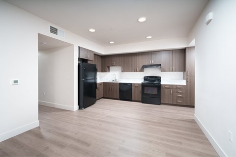 A modern kitchen with wooden cabinets and black appliances.