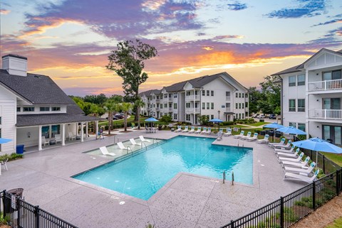 A large outdoor swimming pool surrounded by lounge chairs and umbrellas.