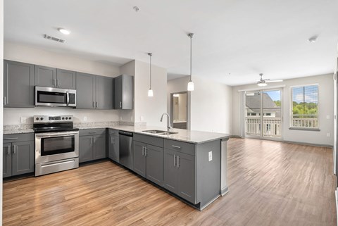 A modern kitchen with wooden floors and stainless steel appliances.
