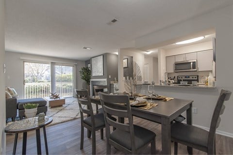 A dining room with a table set for two and a kitchen area in the background.