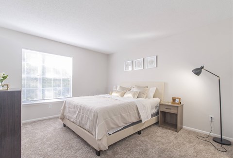 A bedroom with a large bed and a small nightstand.
