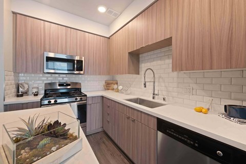 A kitchen with wooden cabinets and a stainless steel dishwasher.