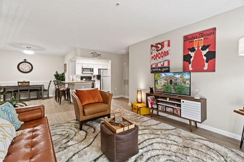 A living room with a brown leather couch and a flat screen TV mounted on the wall.