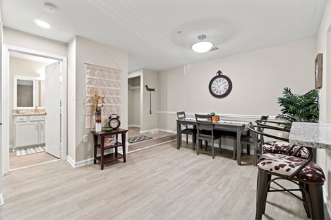 A dining room with a table set for four and a clock on the wall.
