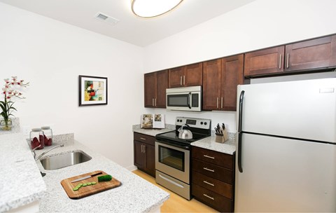 A kitchen with a white refrigerator, brown cabinets, and a white countertop.