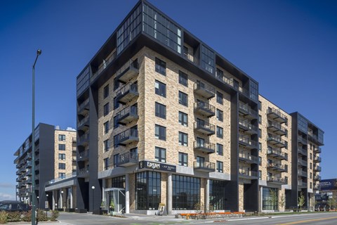 A large, modern building with a flat roof and balconies on the upper floors.