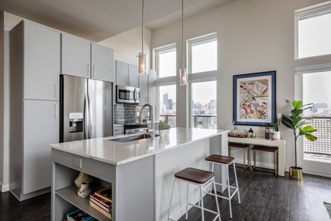 A kitchen with a white counter and bar stools.