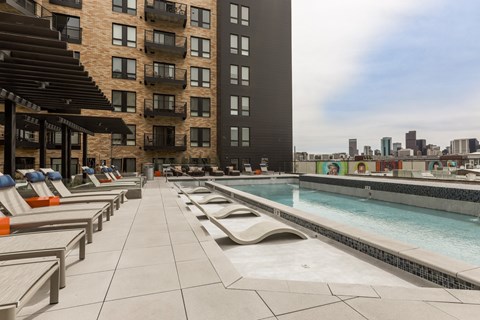 A pool area with sun loungers and a building in the background.