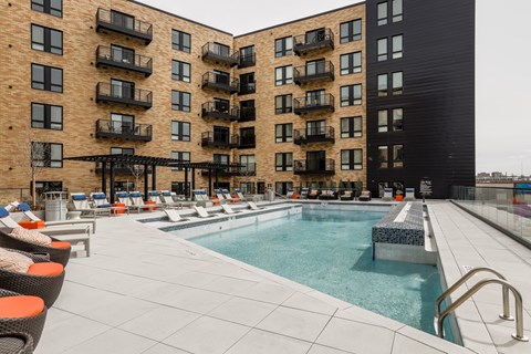 A large outdoor pool area with lounge chairs and a building in the background.