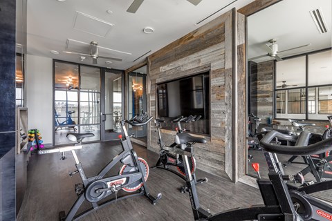 A gym with a wooden wall and a row of exercise bikes.