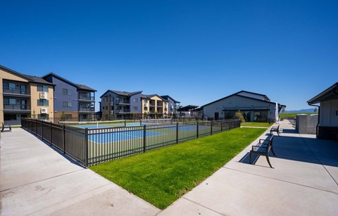 A swimming pool surrounded by a black fence and a grassy area with benches.
