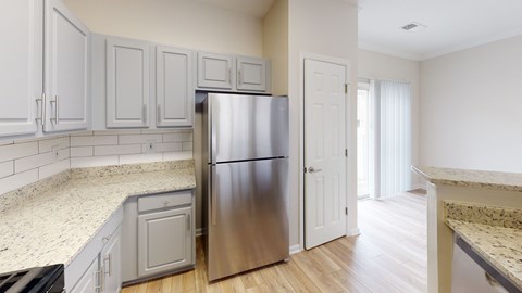 A kitchen with a stainless steel refrigerator and wooden floors.