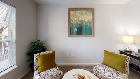 A living room with a sofa, a chair, a coffee table, and a painting on the wall.