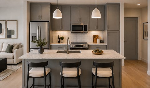 A modern kitchen with a white island and grey cabinets.