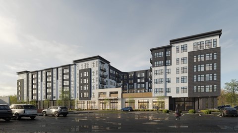 A modern multi-story building with a parking lot in front.