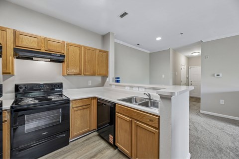A kitchen with a black stove top oven and wooden cabinets.