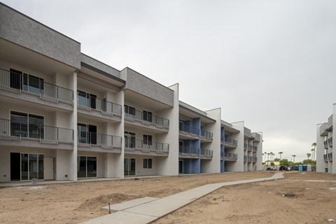 A row of white apartment buildings with balconies and doors are under construction.