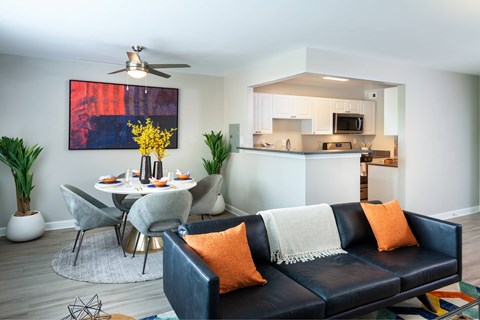 A living room with a black couch and a dining table.