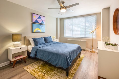 A bedroom with a bed, nightstand, and a ceiling fan.