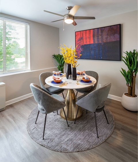 A dining room with a round table and grey chairs.