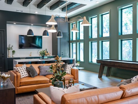 A modern living room with a large orange sofa and a TV mounted on the wall.