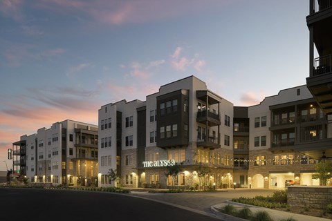 The image shows a modern apartment complex named "The Analysis" at dusk.